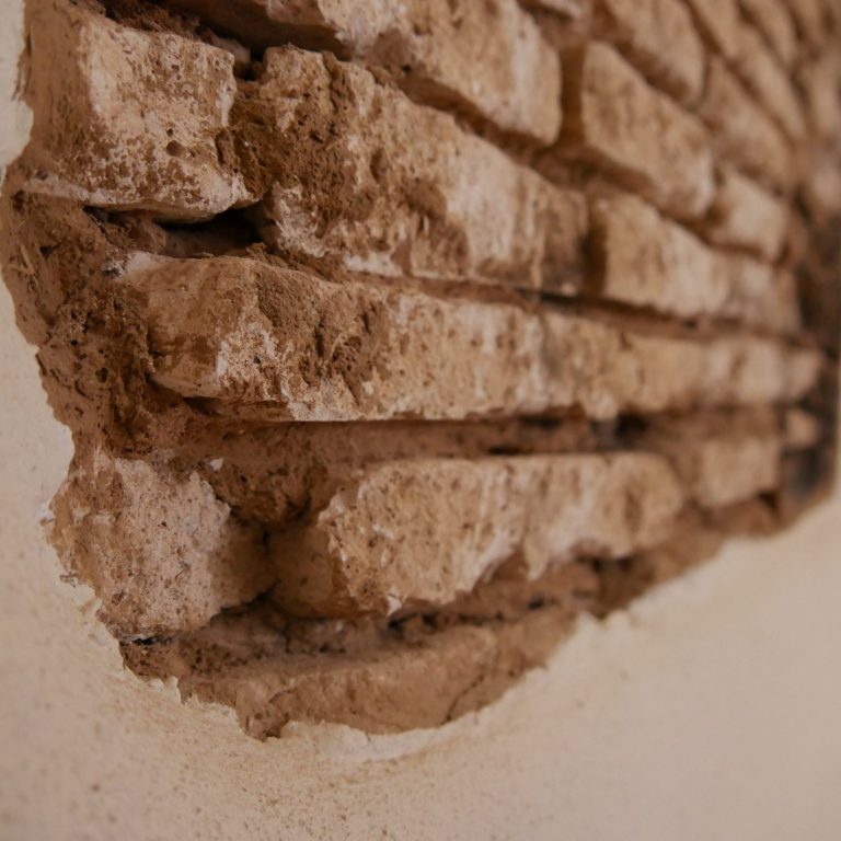 Lehmsteine Lehmwand Nahaufnahme von einer unregelmäßigen, teils freiliegenden Lehmsteinwand.